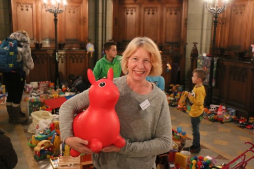Frau mit Spielzeug unter dem Arm, im Hintergrund Kinder